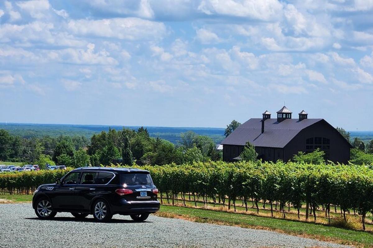 a black car parked on a road in front of a barn