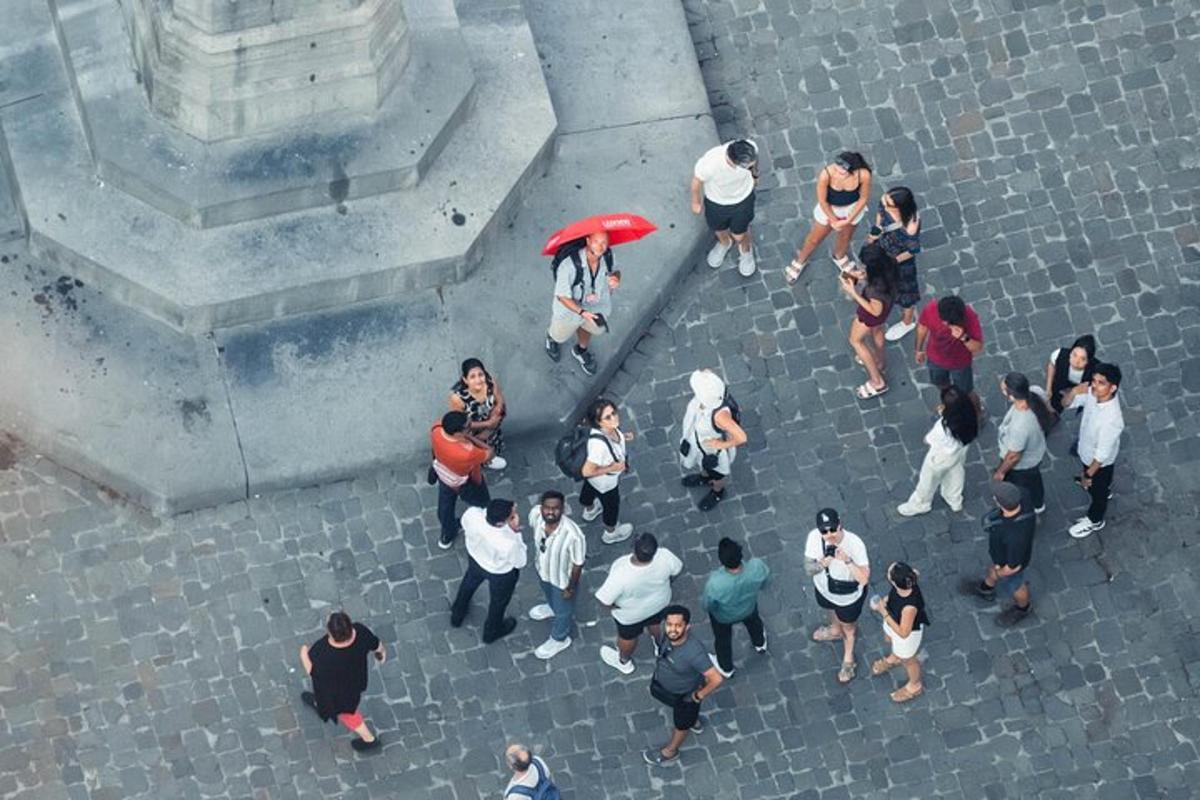 a group of people walking on a street with a red umbrella