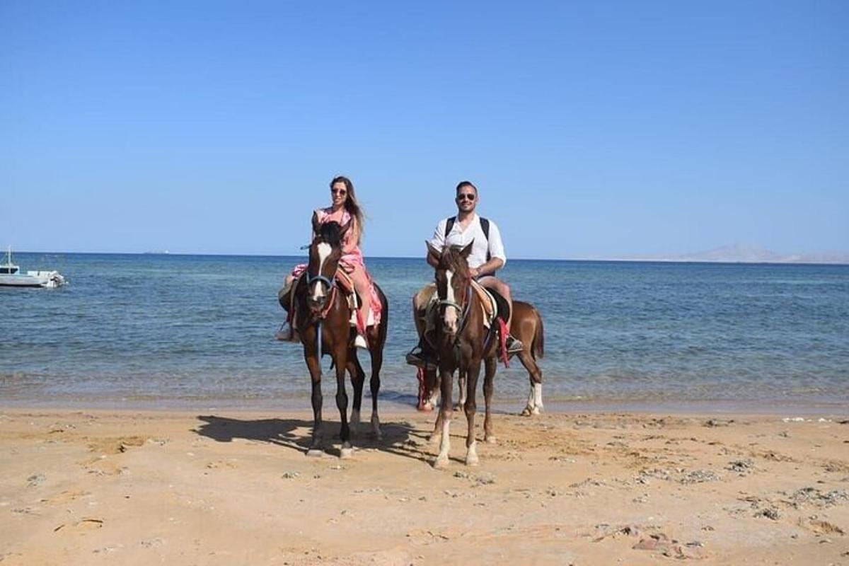 due persone stanno cavalcando cavalli sulla spiaggia