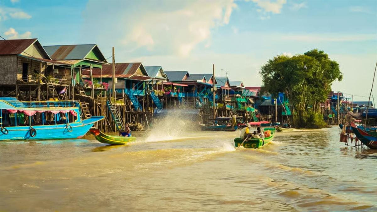 một nhóm thuyền đi dọc theo một con sông có nhà cửa