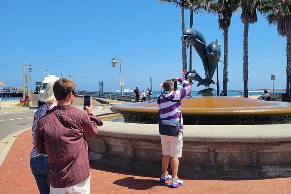 duas pessoas tirando fotos de uma fonte na praia
