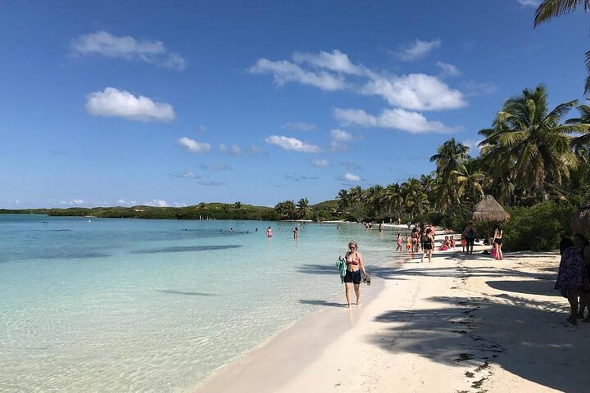 seorang wanita berjalan di pantai dengan orang ramai di dalam air