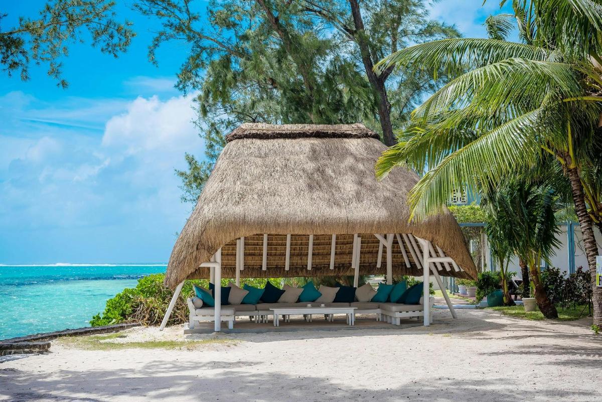a gazebo on the beach with blue pillows