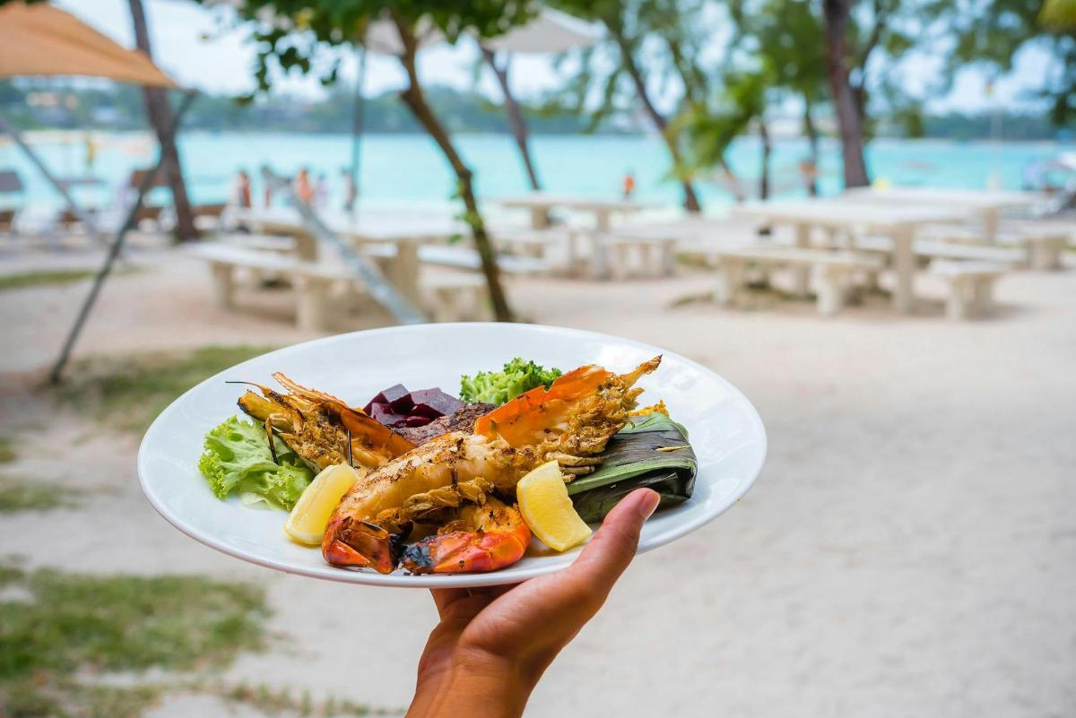 a person holding a plate of food on a beach