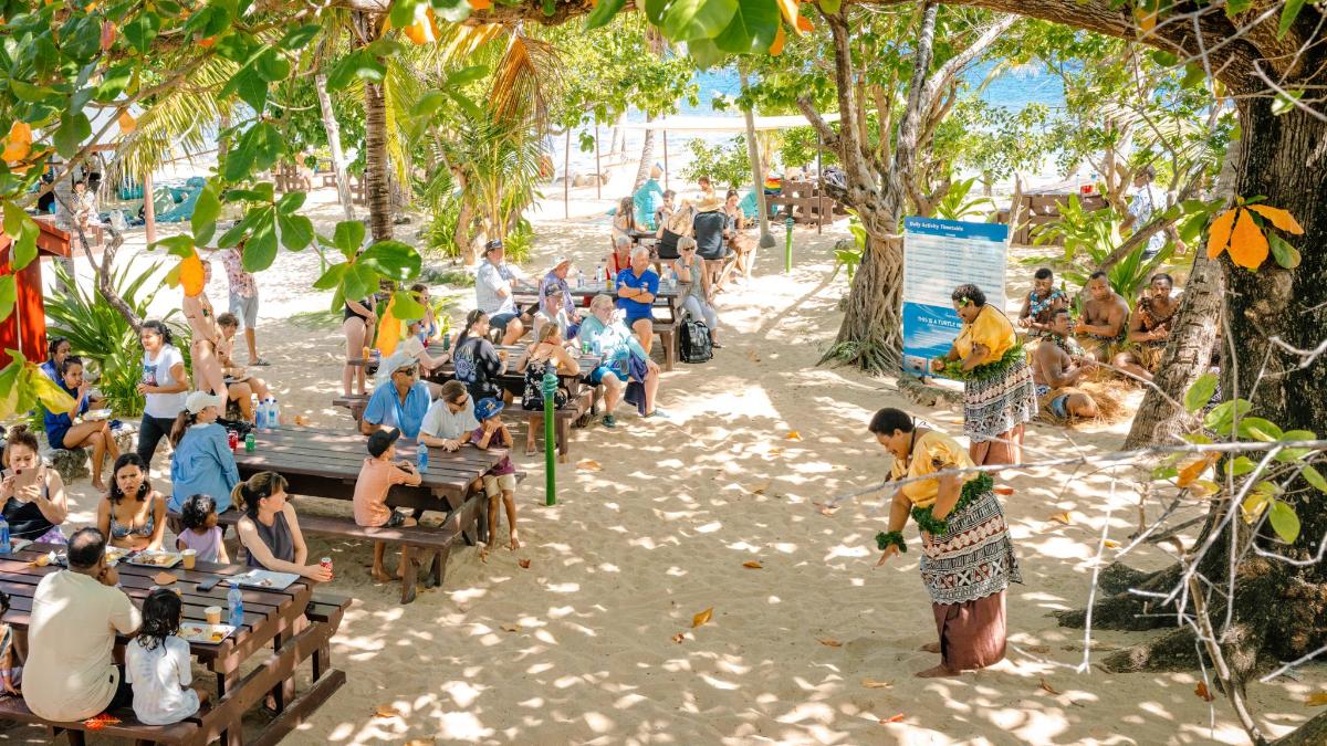 a crowd of people sitting on benches on the beach