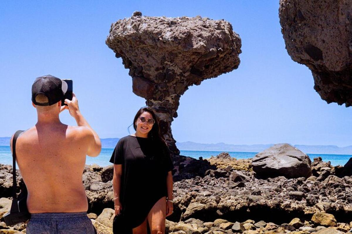 una donna in piedi accanto a un uomo su una spiaggia rocciosa