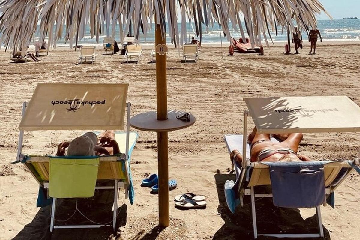 dues persones estirades en cadires de jardí a la platja