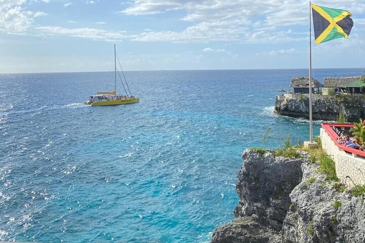 a boat in the ocean with a flag on a cliff