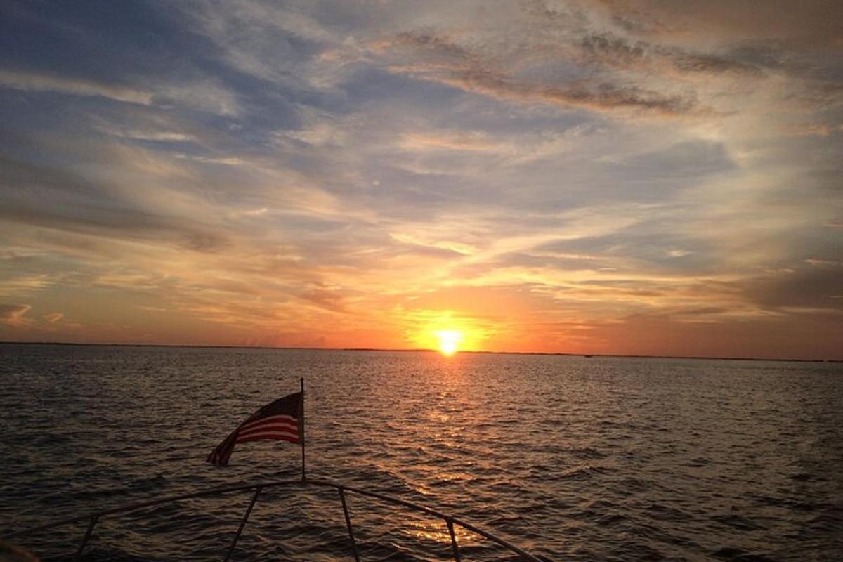 an american flag on a boat in the ocean at sunset