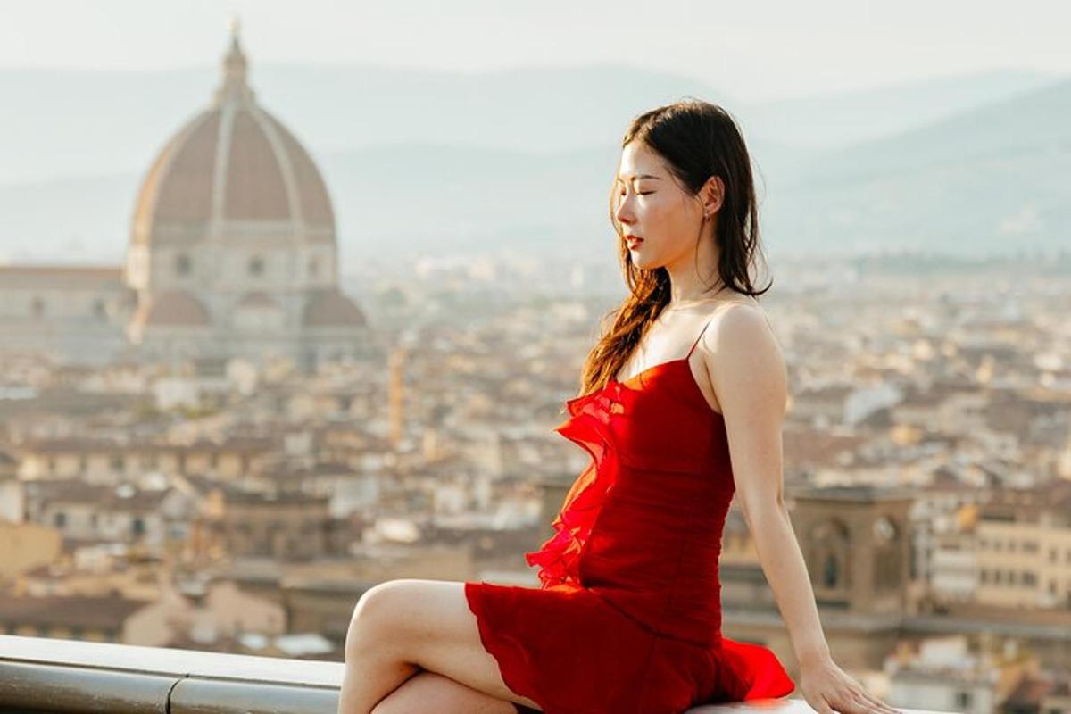 una donna in un vestito rosso seduta su una sporgenza che domina una città