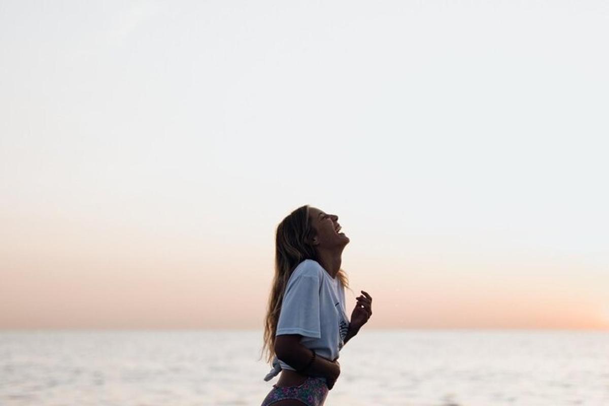 a girl standing on the beach looking up at the sky