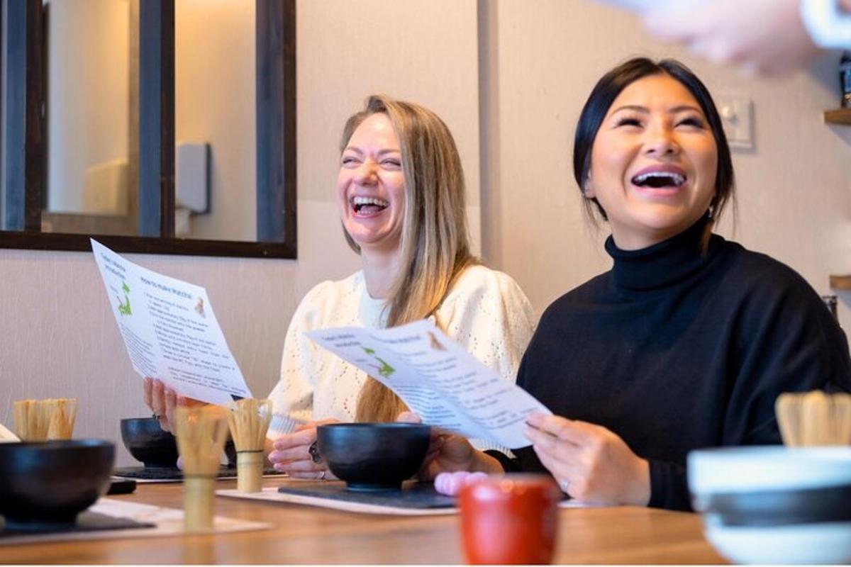 two women laughing while sitting at a table