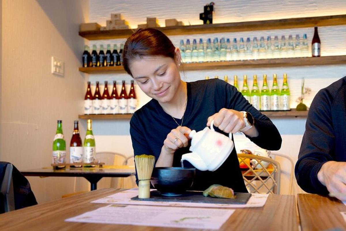 a woman sitting at a table pouring liquid into a bowl