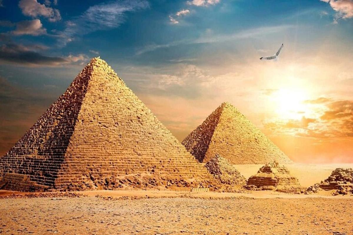 un grup de piràmides en un desert amb la posta de sol