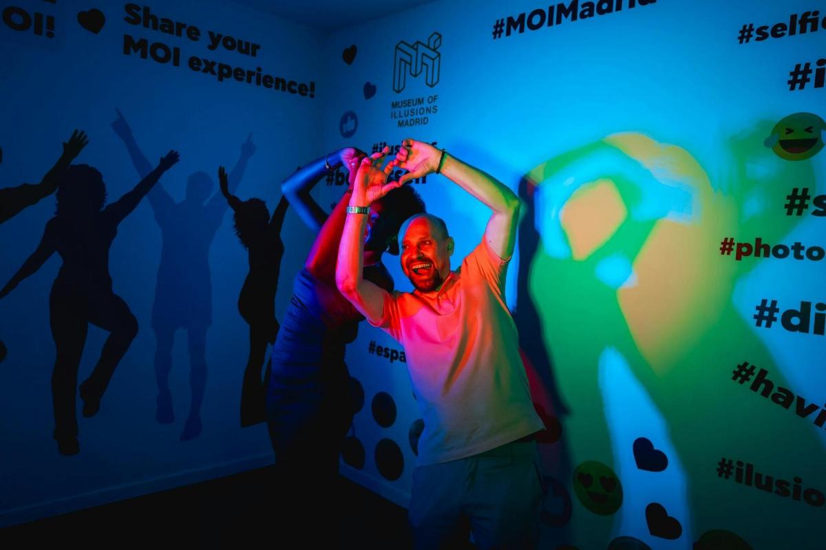 a man dancing in front of a wall with silhouettes of people