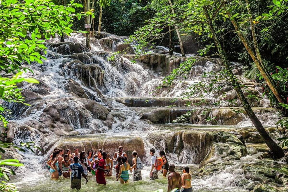 sekumpulan orang berdiri di dalam air berhampiran air terjun
