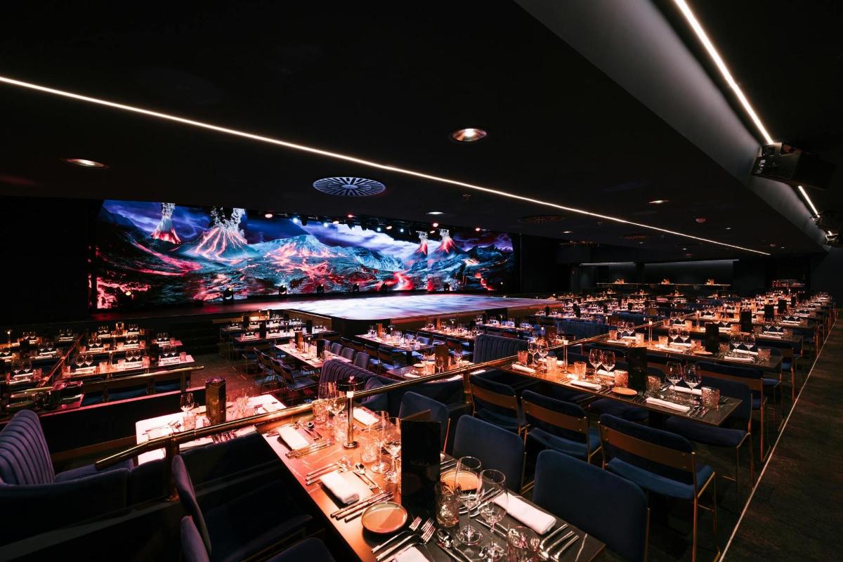 a large room with tables and chairs and a large screen