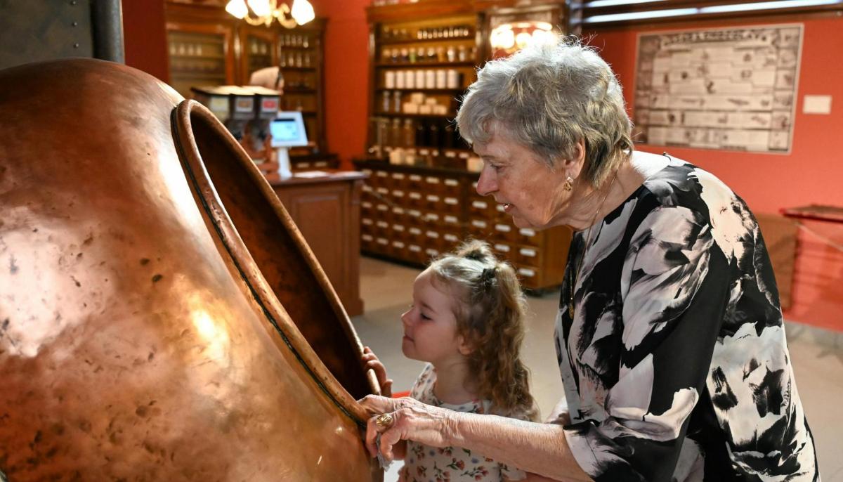 a woman and a little girl looking at a piece of wood