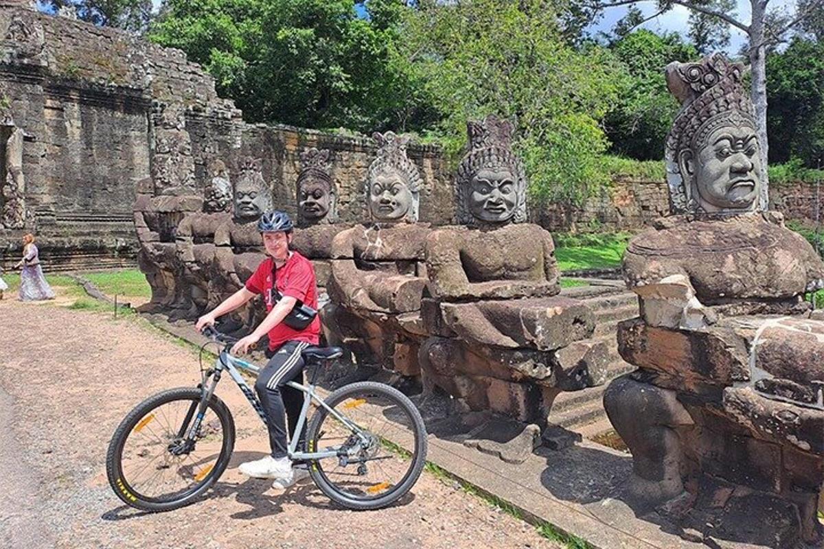 Un hombre en bicicleta frente a unas estatuas