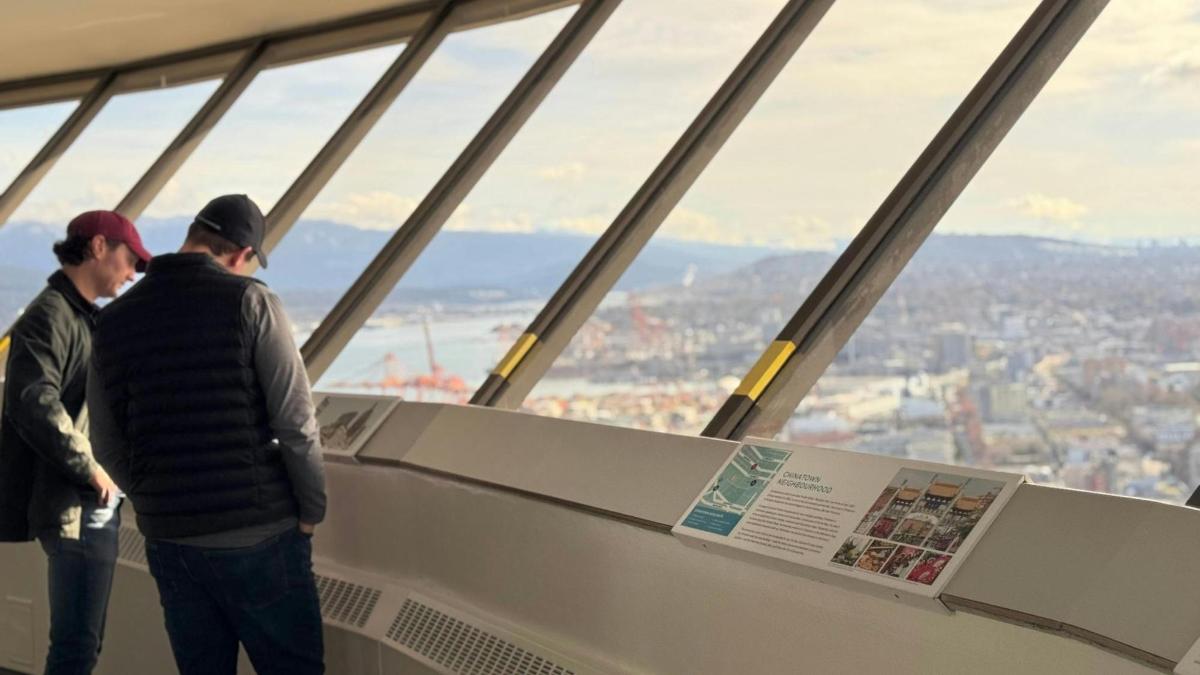 two men looking at the city from the top of an observation tower