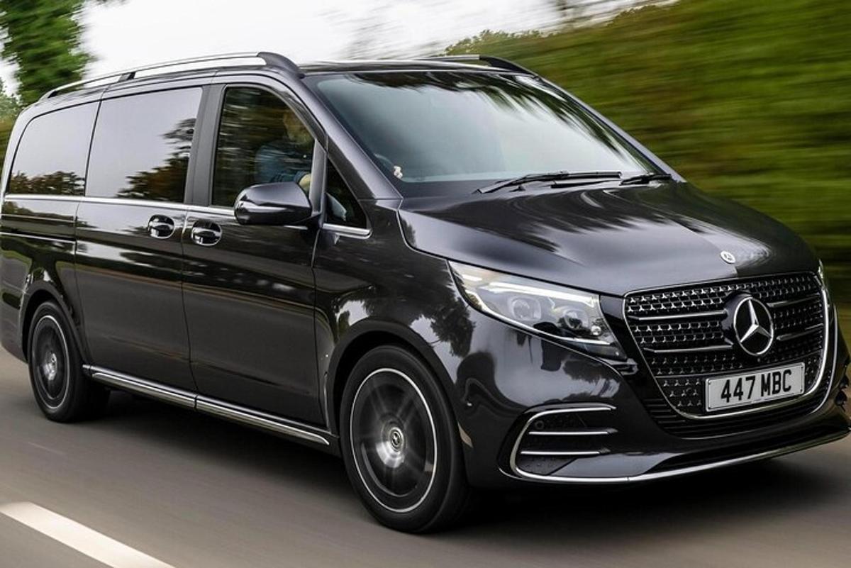 a black mercedes benz minivan driving down a road