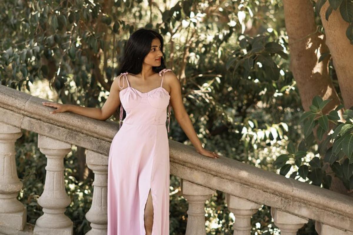 a woman in a pink dress leaning on a railing