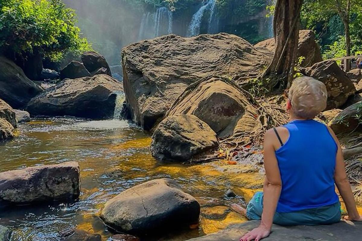 una donna seduta su una roccia che guarda una cascata