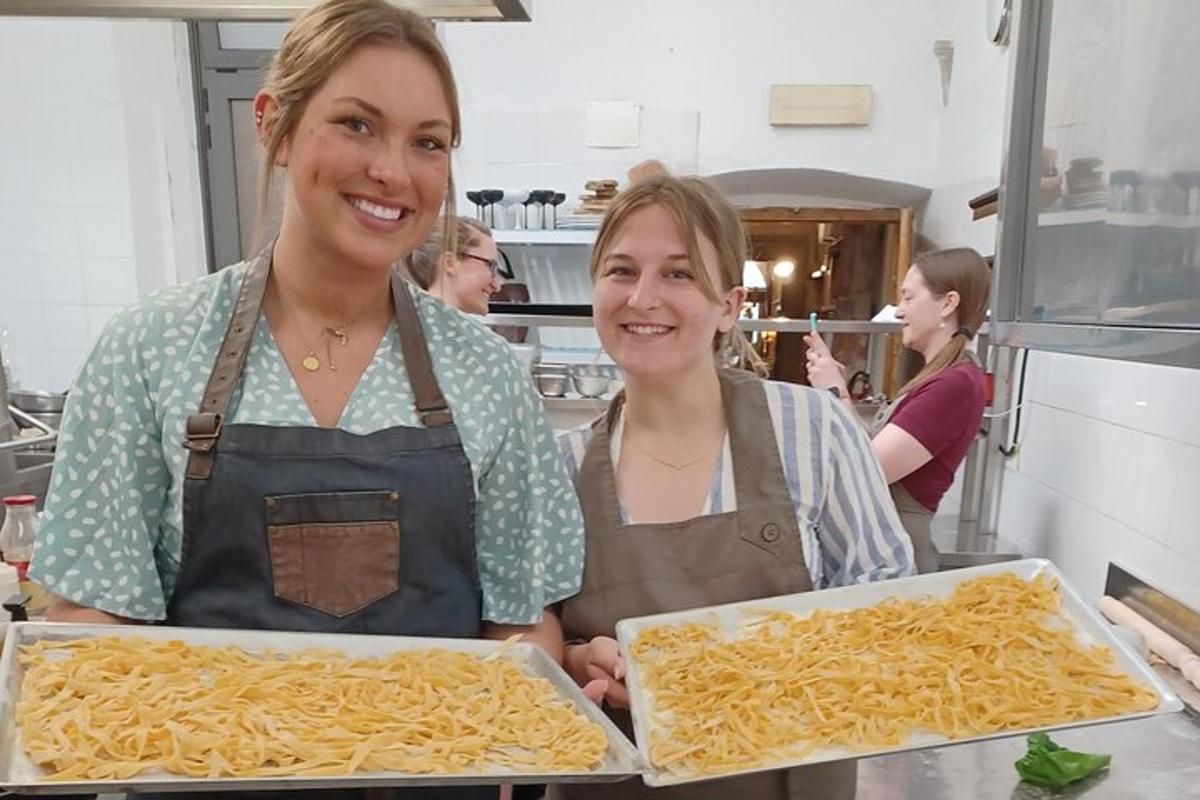 to kvinder i et køkken, der holder en bakke med pasta