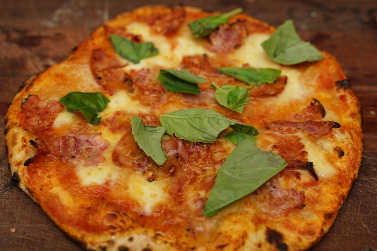 Una pizza con hojas verdes encima.