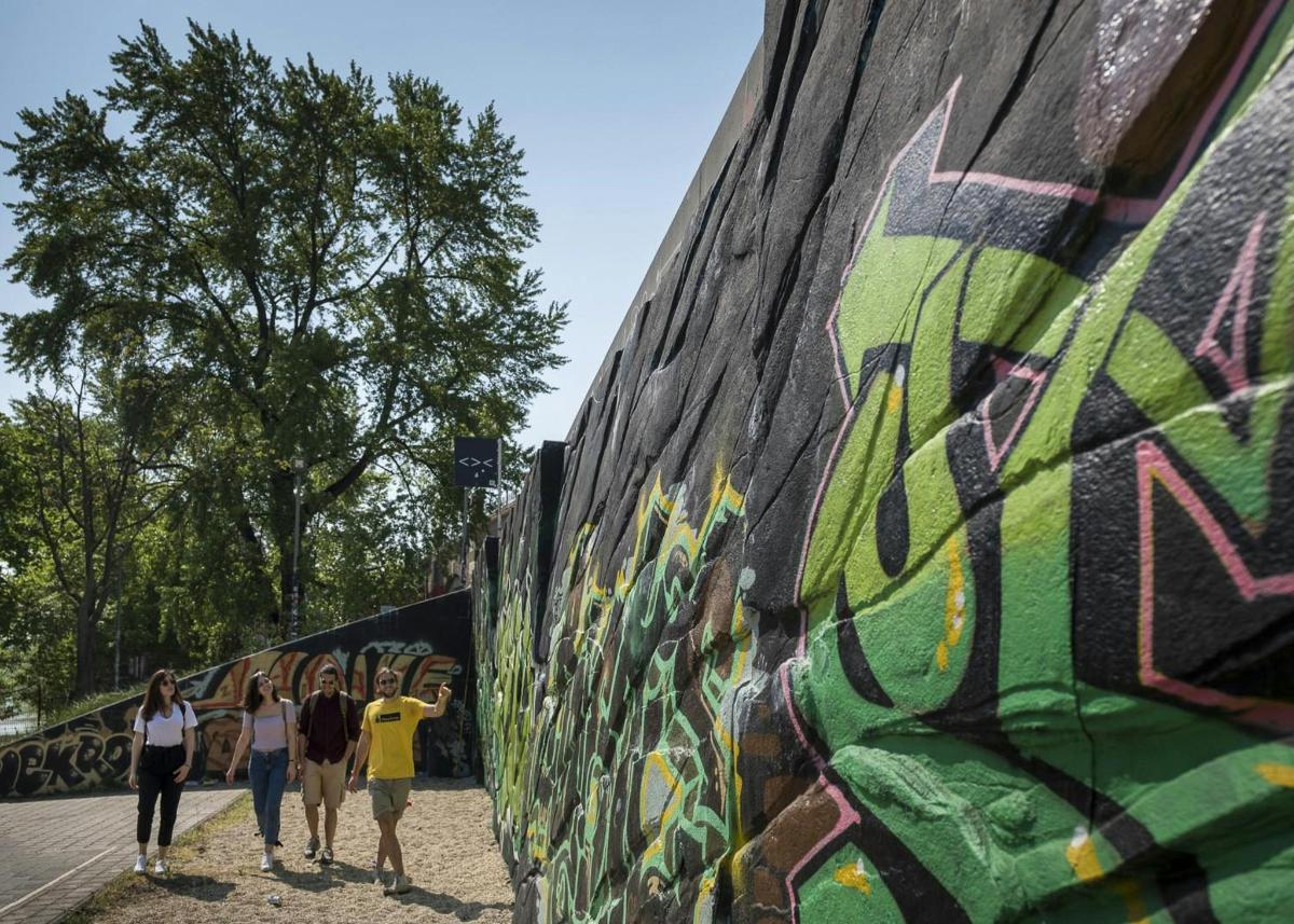 skupina lidí procházejících kolem zdi s graffiti