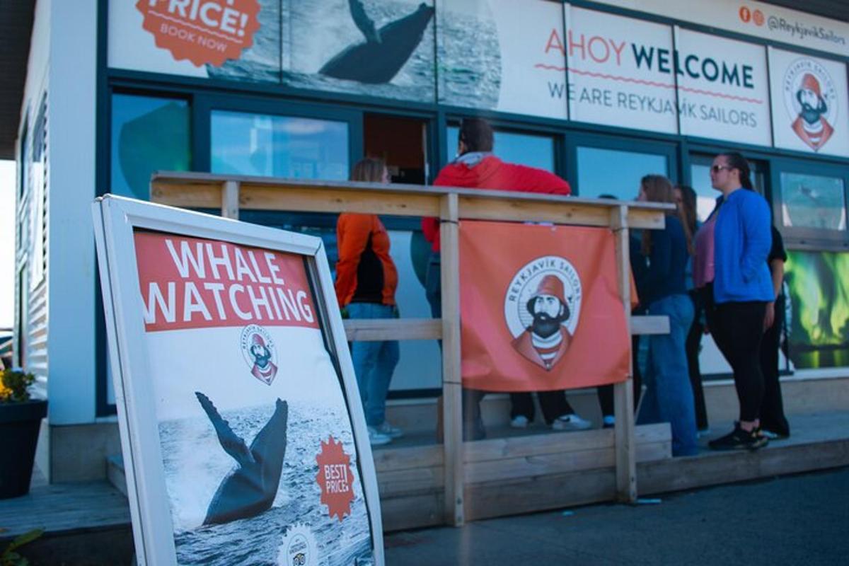 a sign in front of a building with a whale watching sign