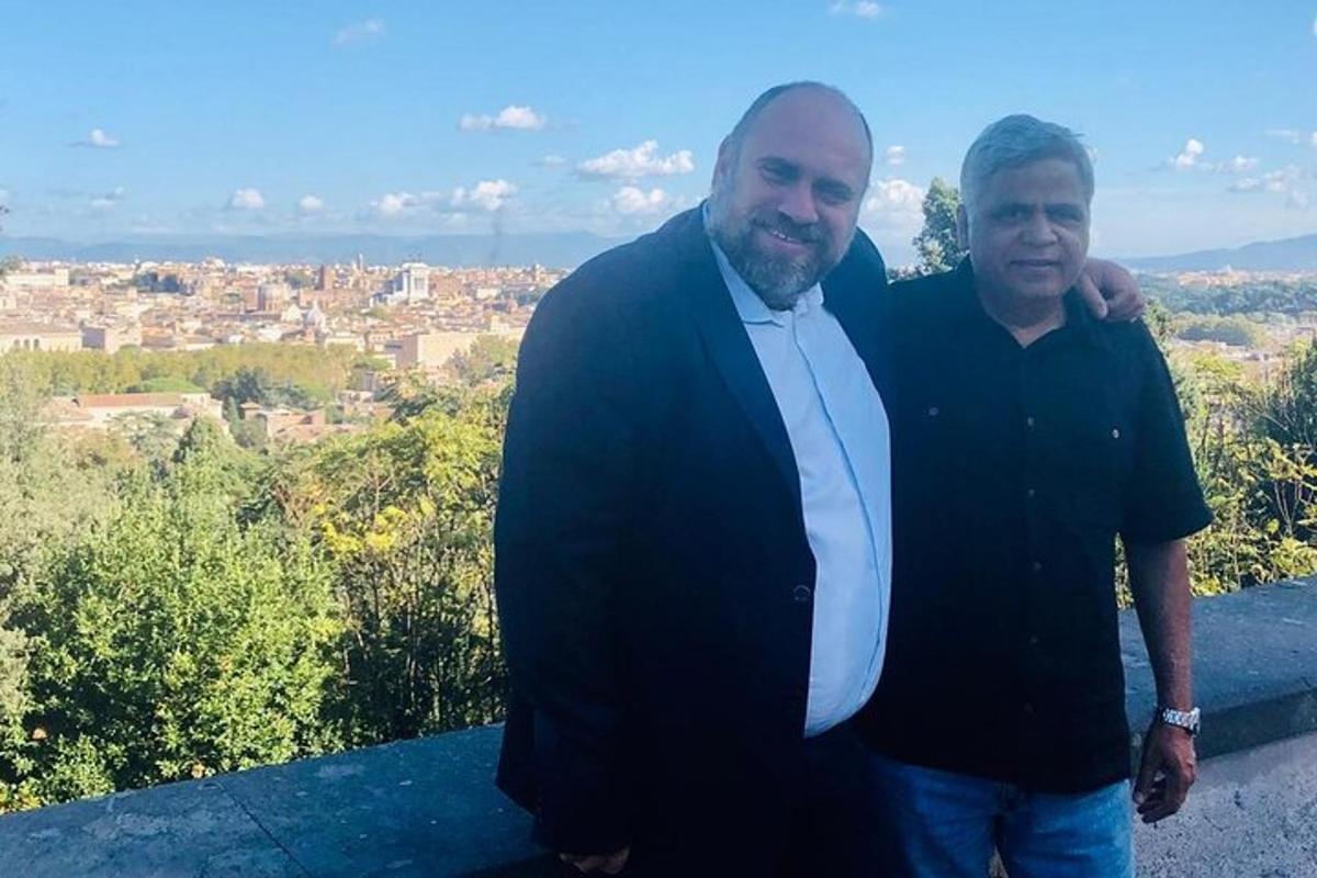 two men standing next to each other in front of a city