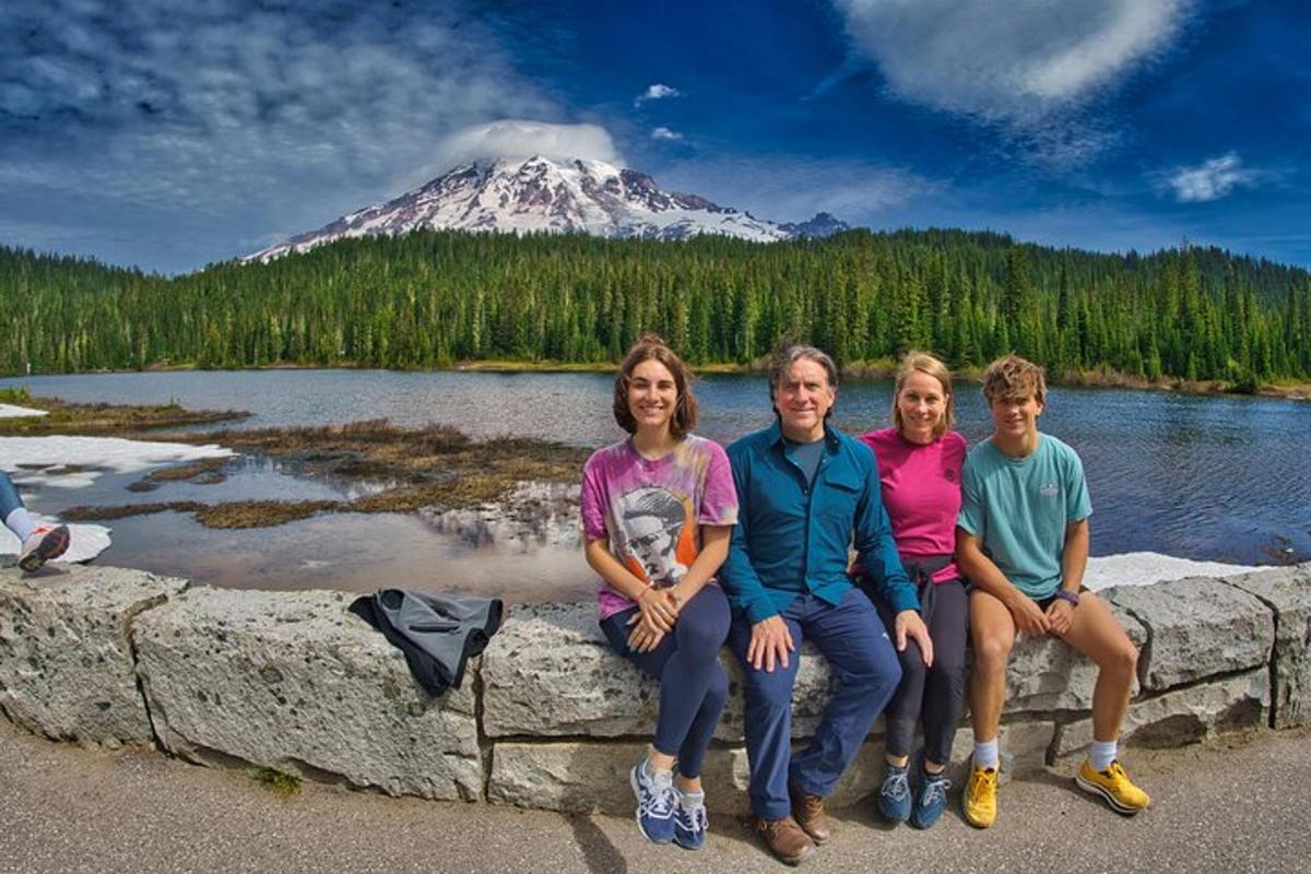 a group of people sitting on a stone wall in front of a mountain