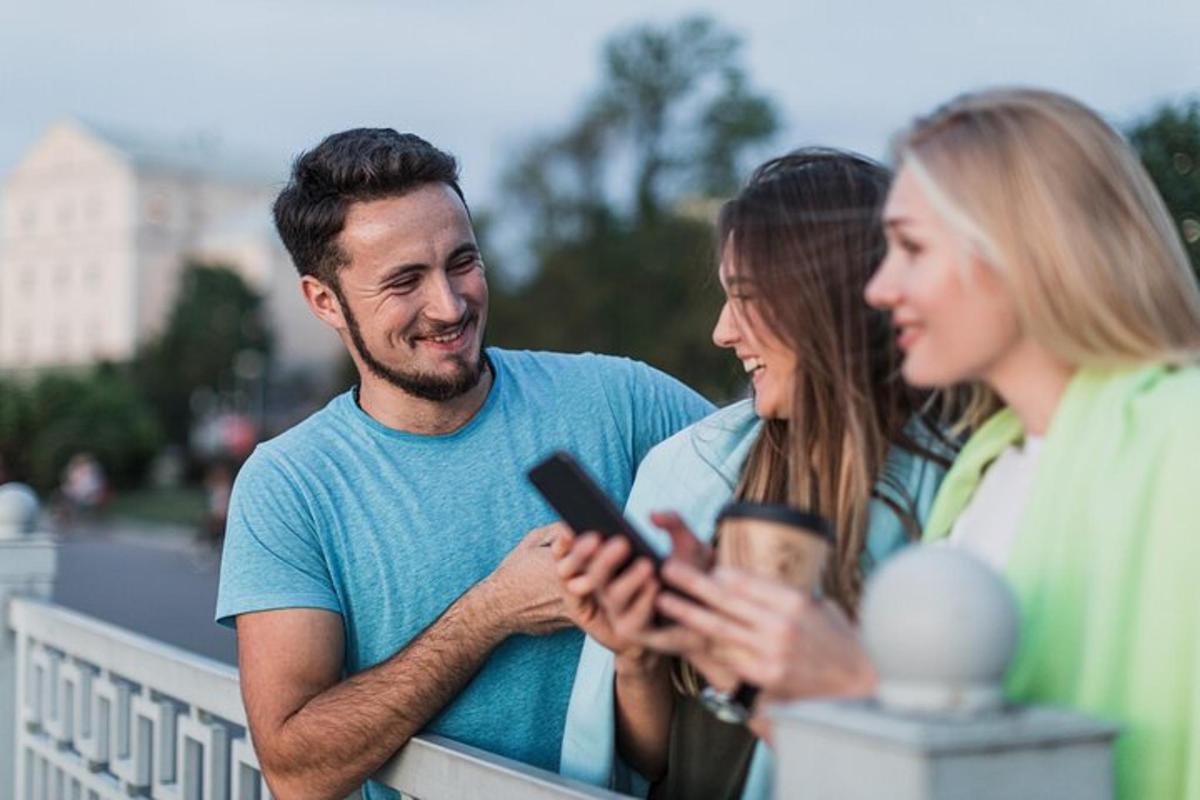 muž a dvě ženy se dívají na mobilní telefon