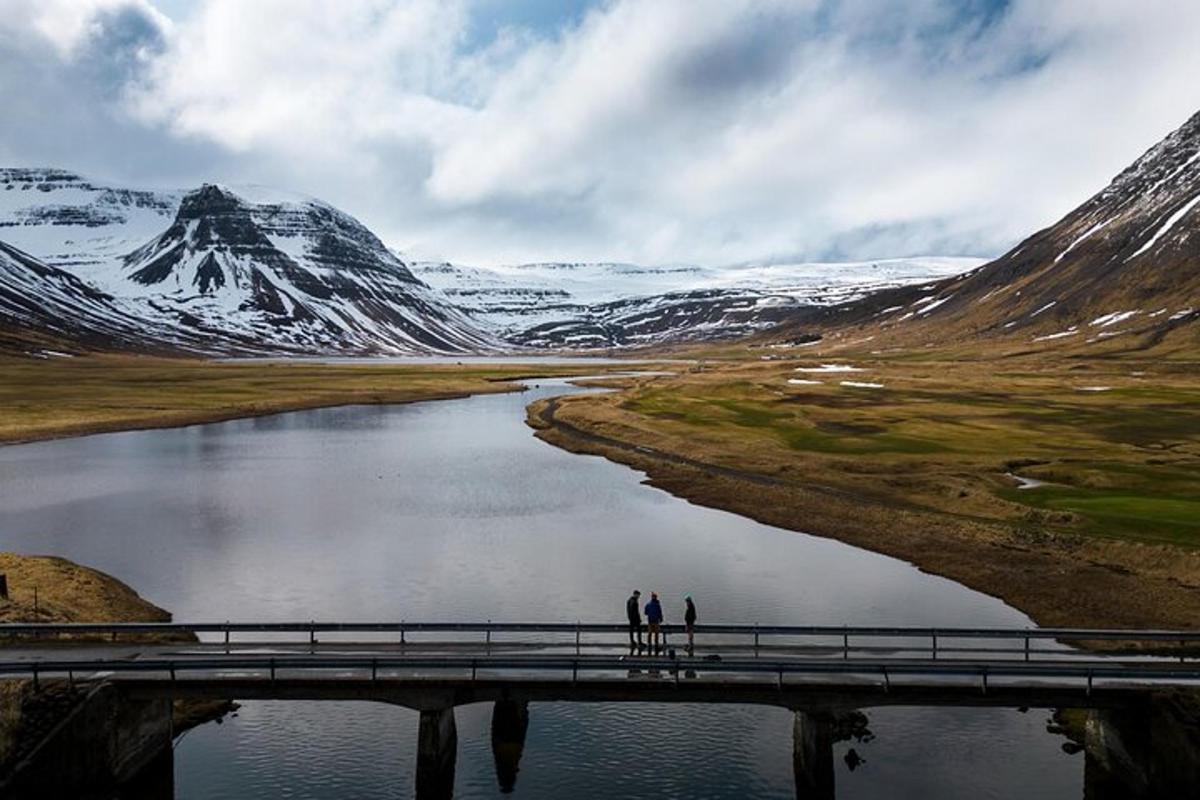 two people standing on a bridge over a river