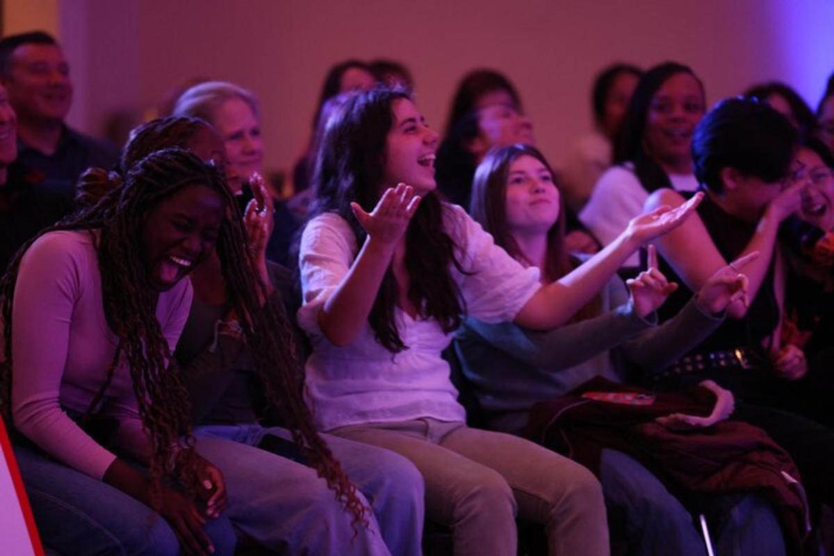 a group of people sitting in a audience applauding