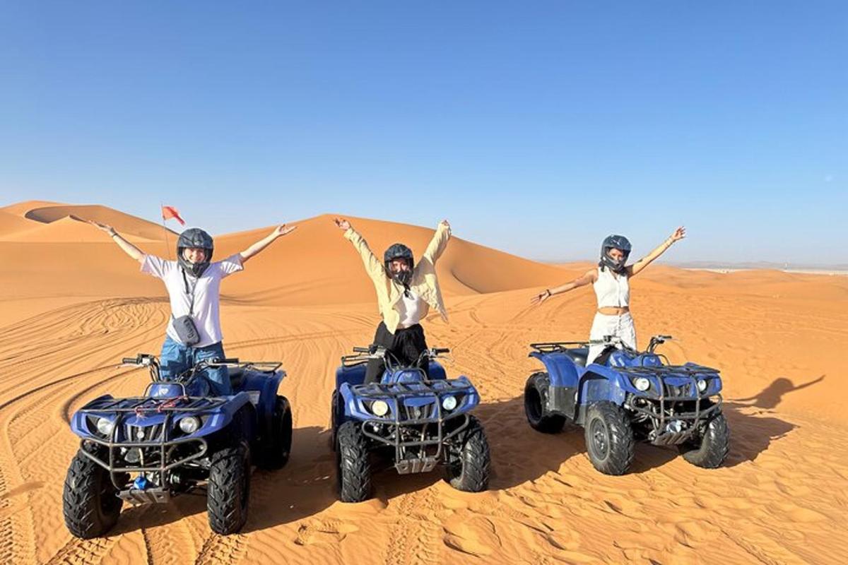 tiga orang di atv di padang pasir