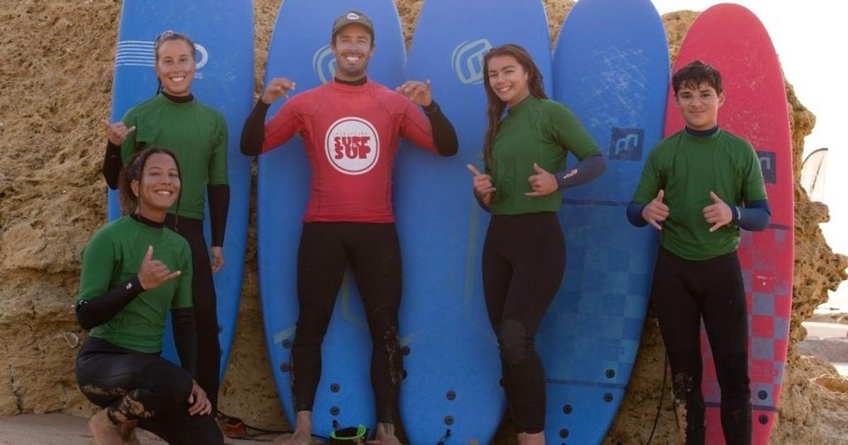 skupina lidí stojících před surfovými prkny