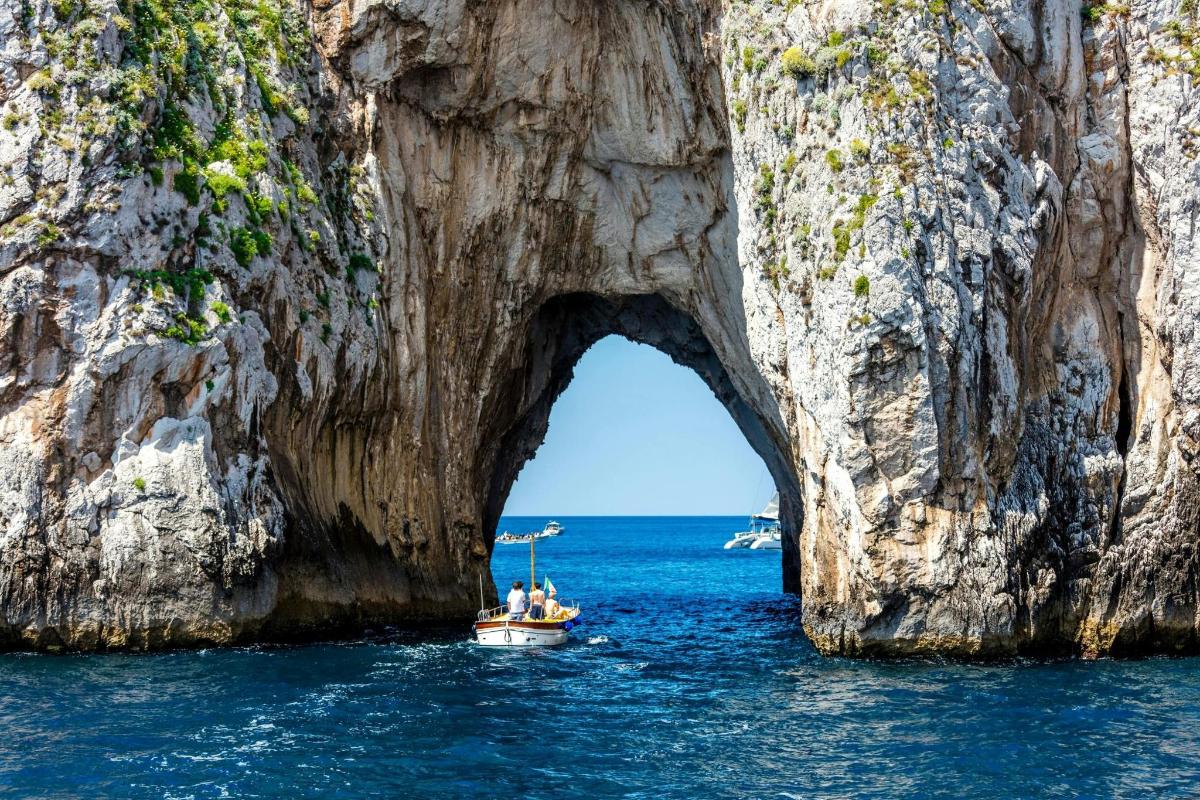 um barco na água em frente a uma formação rochosa