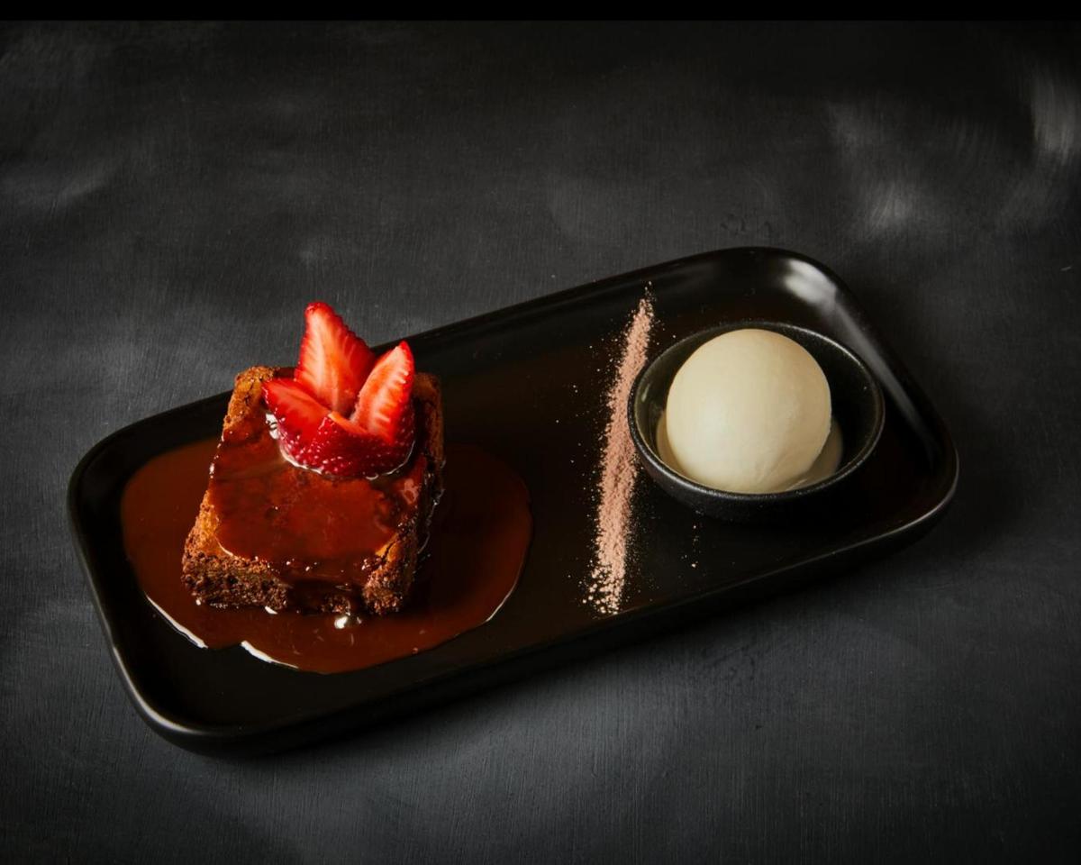 ケーキとアイスクリームの入ったボウルが乗った黒い皿