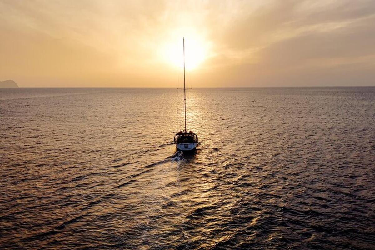 a small boat in the ocean with the sun setting