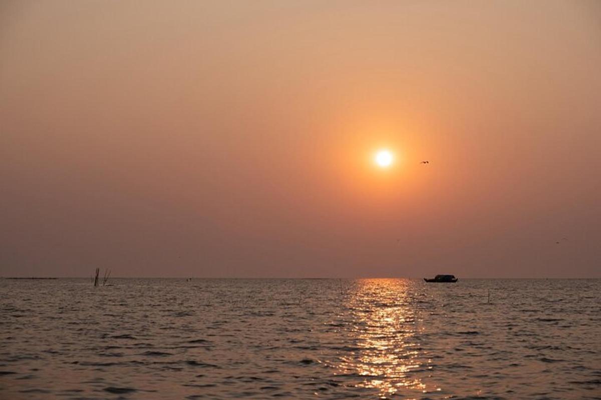 matahari terbenam di atas lautan dengan perahu di dalam air