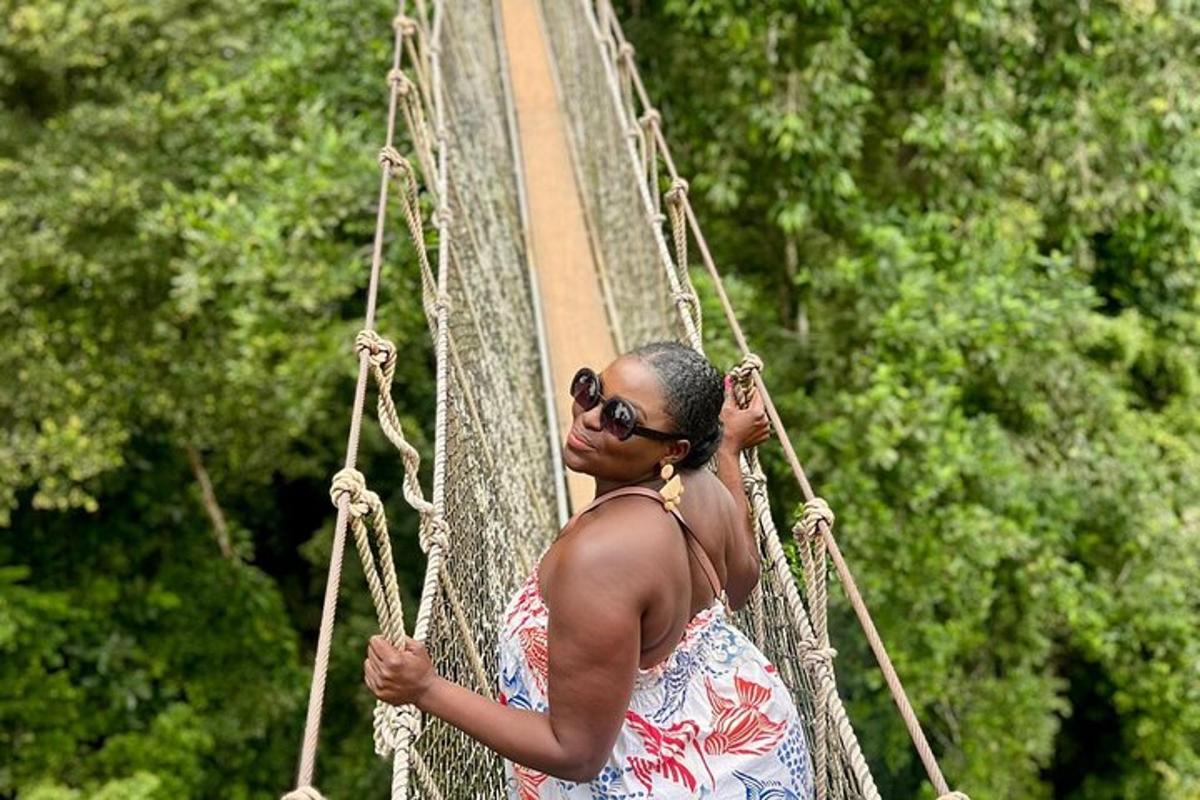 a woman in a dress standing on a suspension bridge