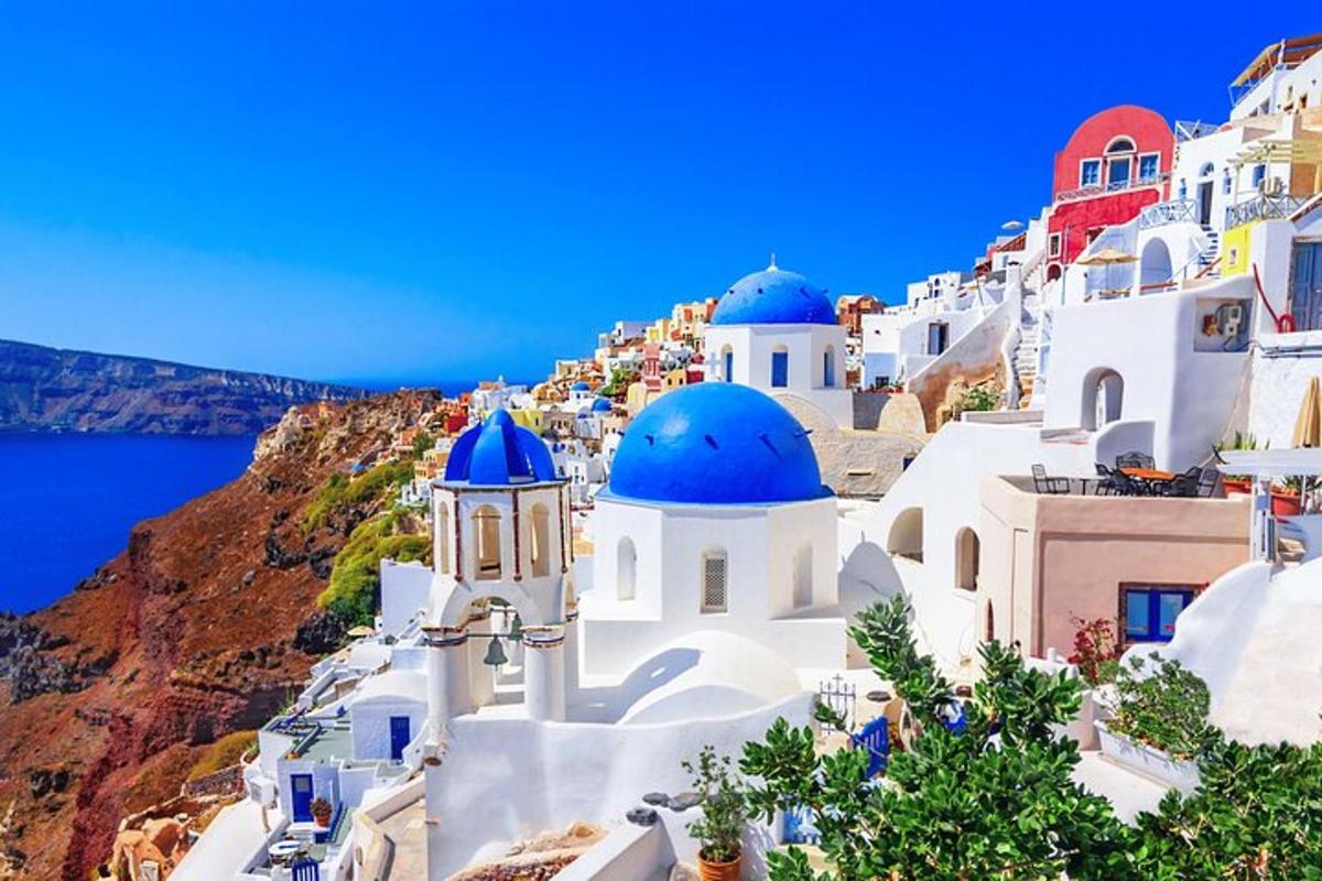 Μια ομάδα λευκών κτιρίων με μπλε θόλους σε έναν απότομο βράχο
