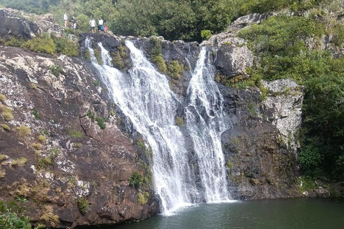 een waterval aan de zijkant van een berg met mensen erop staand