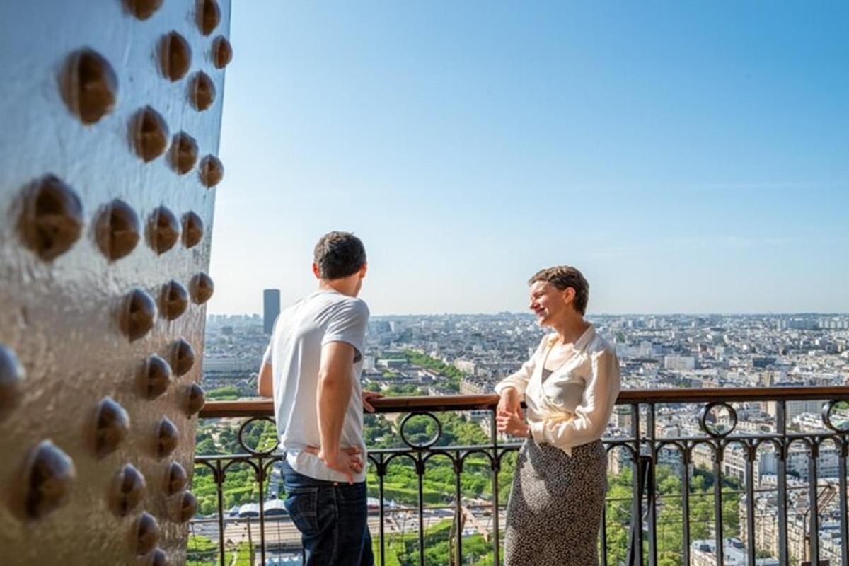 een man en een vrouw staan op een balkon en kijken uit over de stad