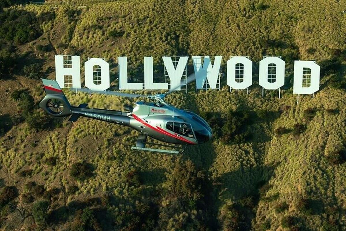 một chiếc máy bay nhỏ bay qua một cánh đồng có chữ hollywood