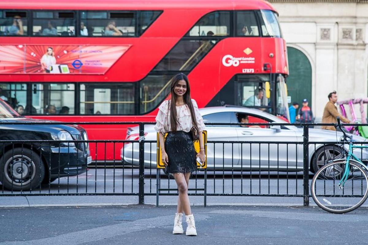 uma mulher parada ao lado de uma cerca com um ônibus vermelho de dois andares