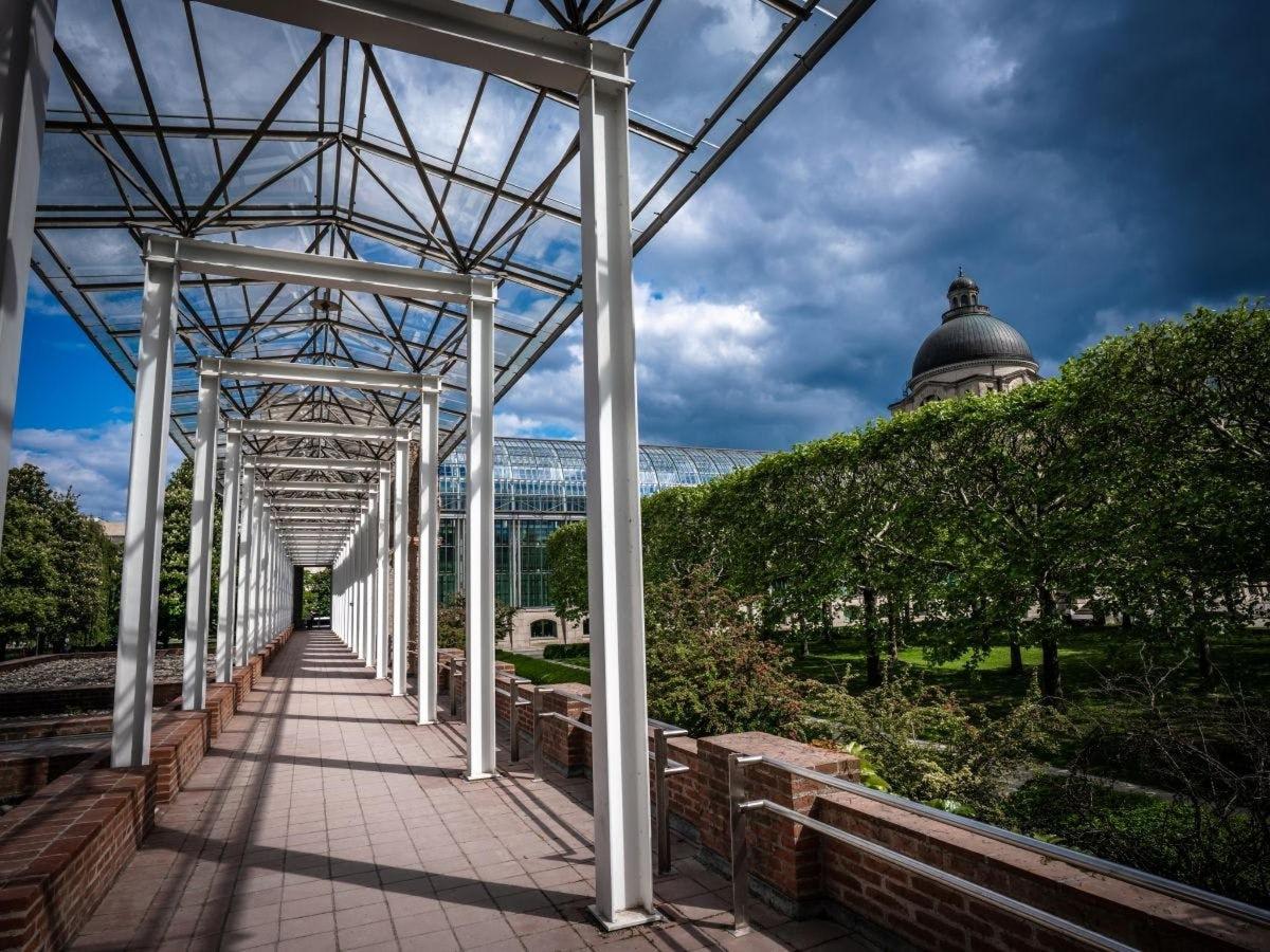 a glass greenhouse with a walkway in a park