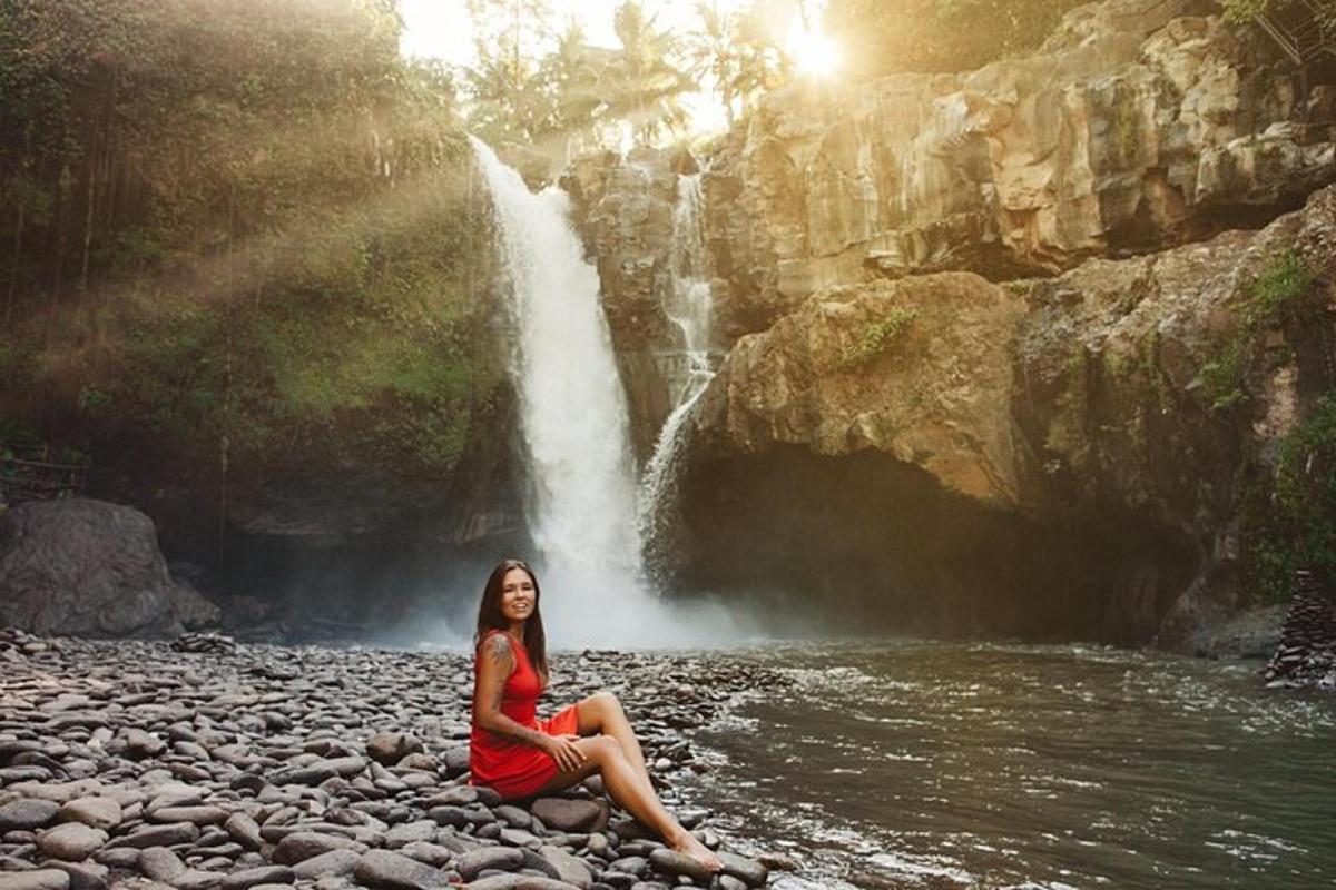 a woman sitting on a rock in front of a waterfall